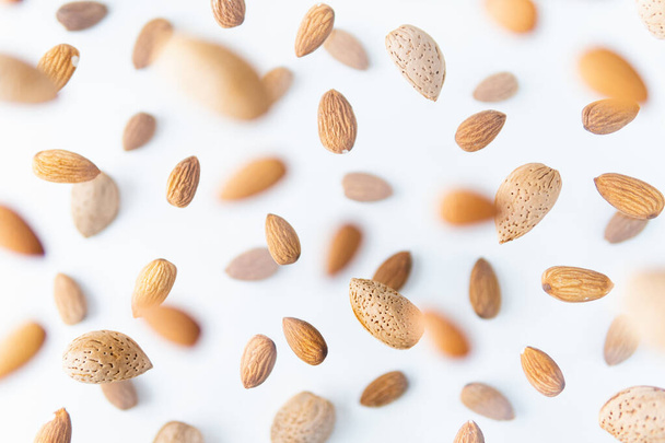 Shelled almond nuts flying above white background, levitation effect. - Foto, Bild