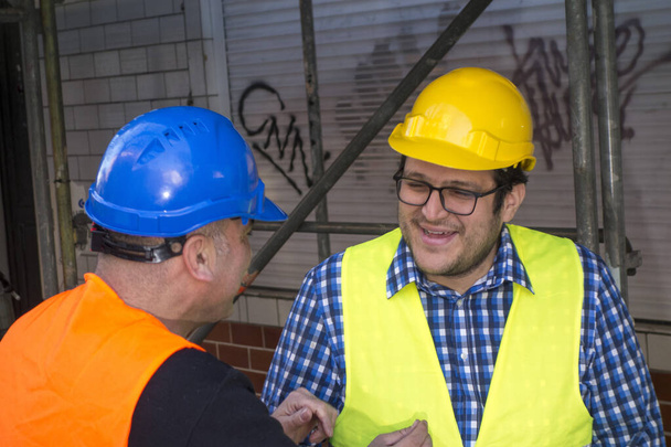 Dos ingenieros civiles hablando y riendo durante las vacaciones de trabajo. Al aire libre
 - Foto, Imagen