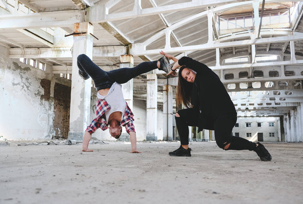 Boy and girl dancing hip-hop in old industrial building. Young couple training dance positions. Street urban lifestyle. - Фото, зображення