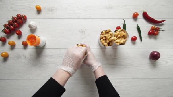 Chef en guantes mover caliente y delicioso papas fritas a bolsa de papel
 - Metraje, vídeo