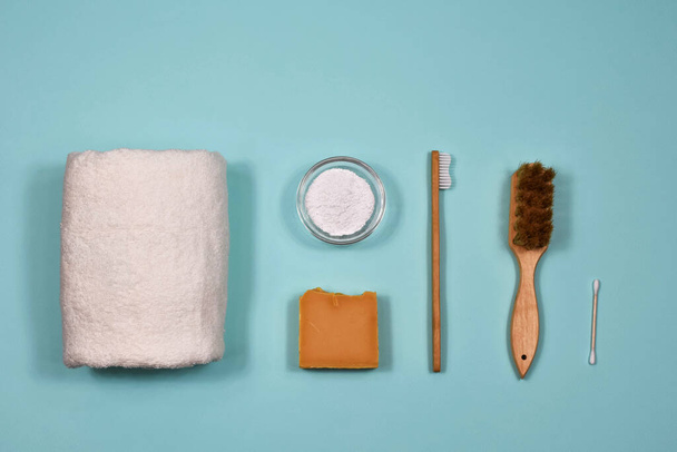 Concepto de cero residuos. Cepillo de dientes, polvo dental, toalla, jabón y cepillos sobre fondo azul. Vista desde arriba
. - Foto, Imagen
