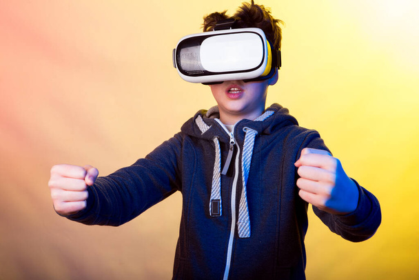Émotions et joie d'un jeune homme lorsqu'il utilise la réalité virtuelle. Photo d'un jeune homme vêtu d'une veste de sport sombre sur fond de nuances de jaune et de violet clair
 - Photo, image