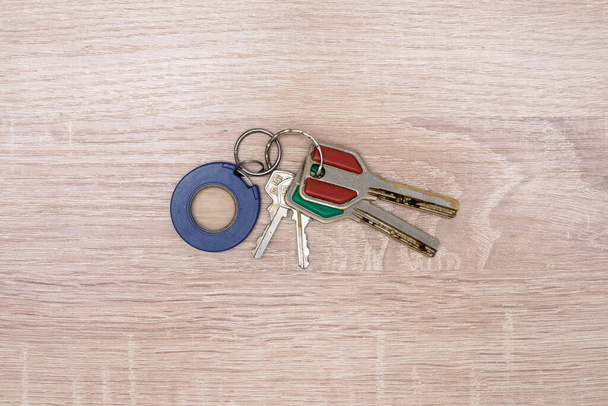 Velho duas chaves grandes, duas chaves pequenas e um chaveiro encontram-se em um fundo de madeira, na mesa
 - Foto, Imagem