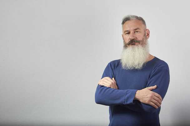 Portrait of mature gray-haired bearded man in blue sweatshirt on grey background, selective focus - Fotografie, Obrázek