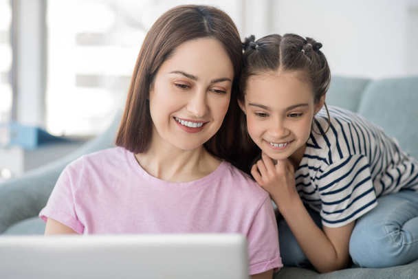 Happy and beautiful mother with daughter looking at laptop. - Photo, image