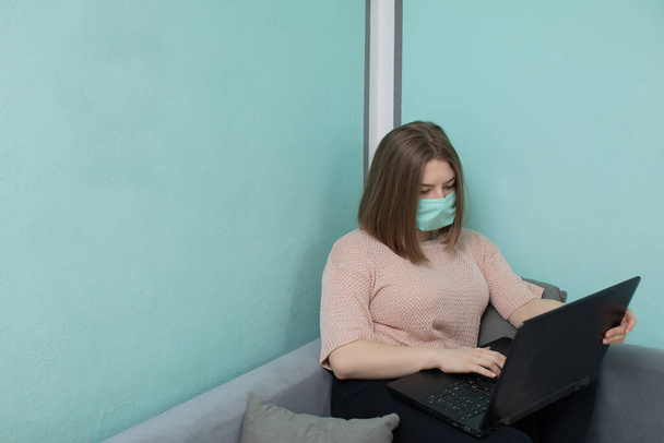 In the academic room you must be in a face mask to reduce the risk of infection. The teenager sits on a bed in a dormitory in a protective mask. - Foto, imagen
