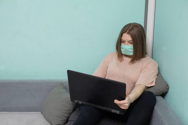 In the academic room you must be in a face mask to reduce the risk of infection. The teenager sits on a bed in a dormitory in a protective mask. - Фото, зображення