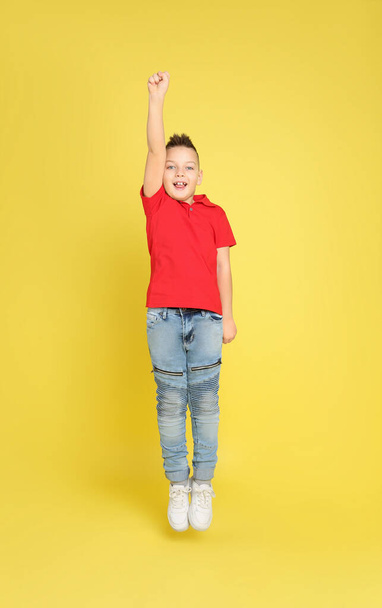 Cute little boy jumping on yellow background - Фото, зображення