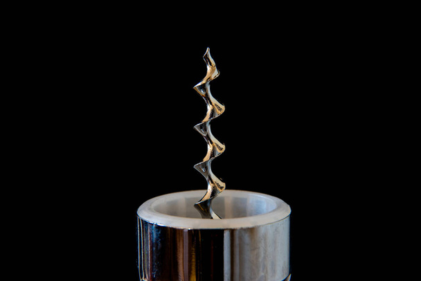 A closeup photograph of a corkscrew, isolated against a black background. - Photo, Image