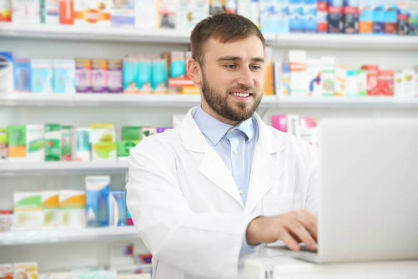 Professional pharmacist working on laptop in modern drugstore - Foto, Imagem