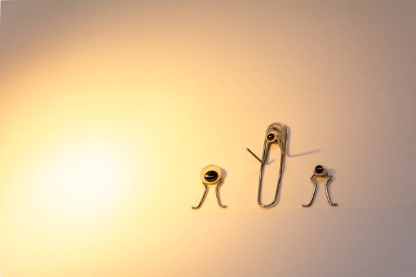creative idea. 3 metal paper clips with eyes depicting aliens look at a ray of light. white background. empty space. - Φωτογραφία, εικόνα