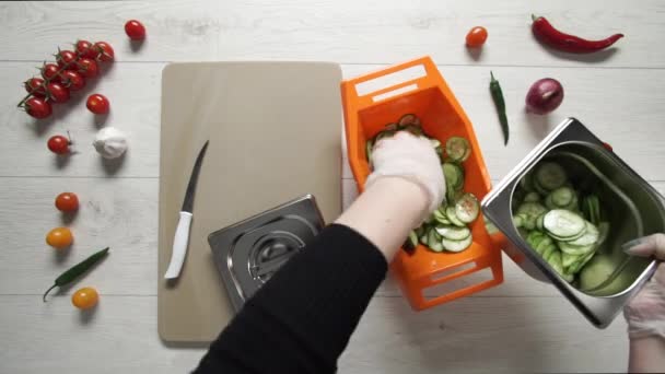 Şef plastik kaseden bir parça salatalık alıp metal konteynıra koyuyor. - Video, Çekim