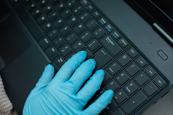In times of personal infection, special precautions such as rubber gloves are necessary. Laptop keyboard used by a teenager in rubber gloves for safety. - Photo, Image