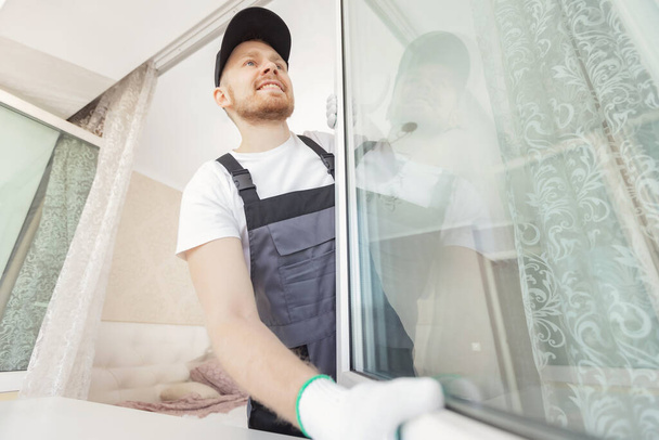 Worker man installs plastic windows and doors with double-glazed white - Photo, Image