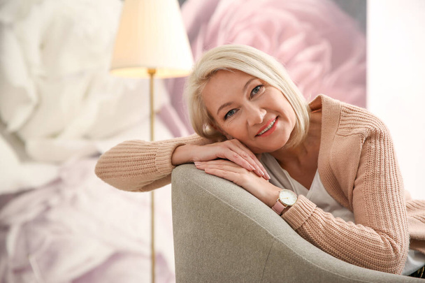 Kaunis kypsä nainen sohvalla kotona
 - Valokuva, kuva