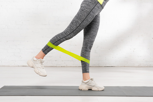 cropped view of woman exercising with resistance band on fitness mat - Fotografie, Obrázek