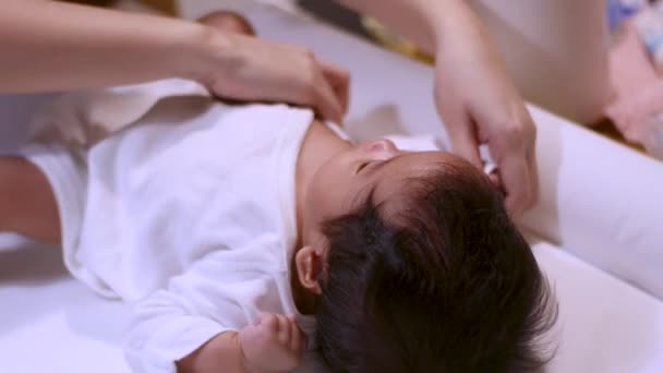 4k Asijský rodič dát na župan pro kojence holčička po koupeli doma, teplé a šťastné, útulné, župan, dítě ležící na stole, denní čas, čistá hygiena, anti bakterie, černé vlasy, bílé oblečení - Záběry, video