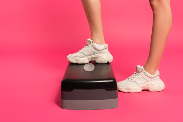 bijgesneden weergave van sportvrouw staan op stap platform op roze  - Foto, afbeelding