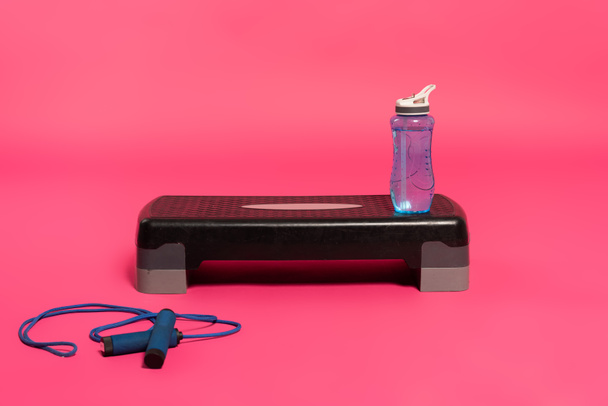 sports bottle with fresh water on step platform near skipping rope on pink  - Foto, Imagem