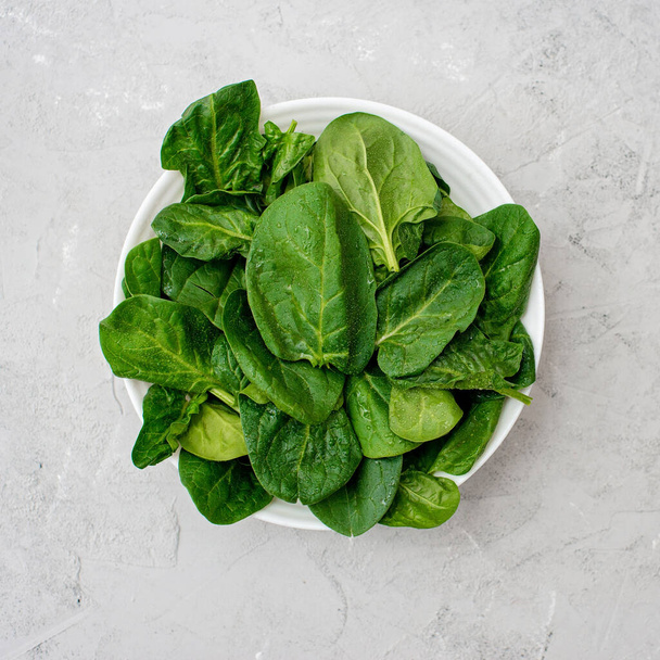 Clean food concept. Leaves of fresh organic spinach greens in a plate on a light background. Healthy detox spring-summer diet. Vegan Raw Food. - Photo, Image