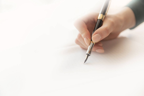 Escritora joven escribe poesía con pluma estilográfica en hoja de papel, luz solar cálida
 - Foto, Imagen