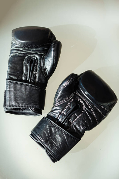 Black boxing gloves lie on a white table. - Foto, afbeelding