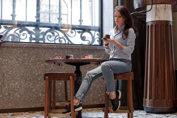 Girl in a beautiful trendy cafe. Girl at the table with a cup of coffee - Фото, изображение