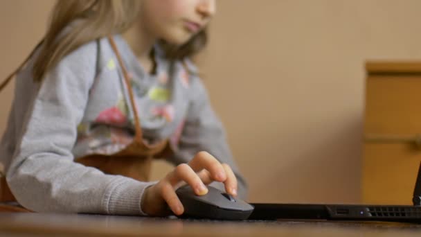 Malá dětská ručička drží počítačovou myš na pozadí notebooku. Vzdálené on-line vzdělávání během karantény a self-izolace při pobytu doma - Záběry, video
