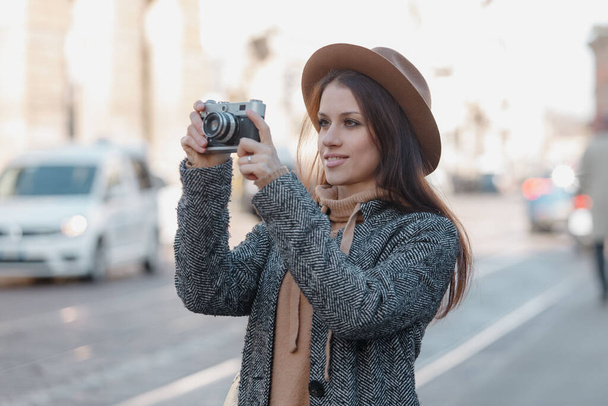 Beautiful brunette tourist girl holds a camera in her hands and looks into the lens - Fotó, kép
