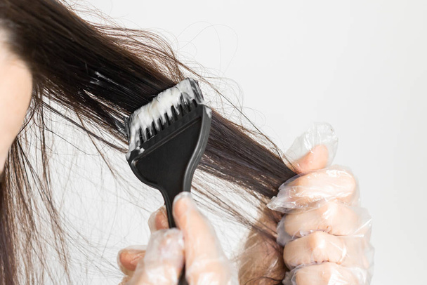 Primeros planos mujer manos teñir el cabello con un cepillo negro. Coloración del cabello blanco en casa
.. - Foto, Imagen