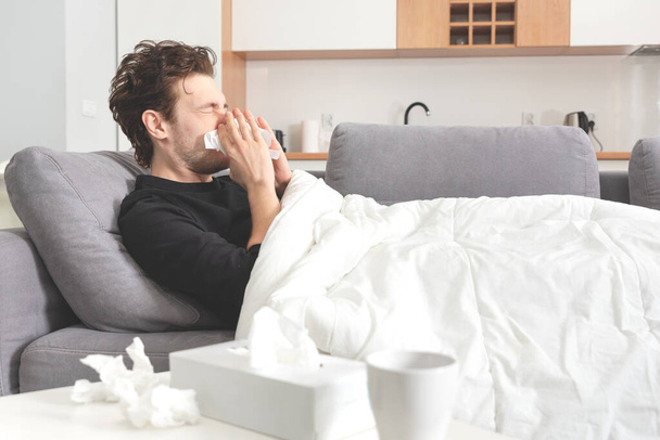 Sick man lying on sofa and blowing nose. Healthcare, disease concept - Foto, imagen