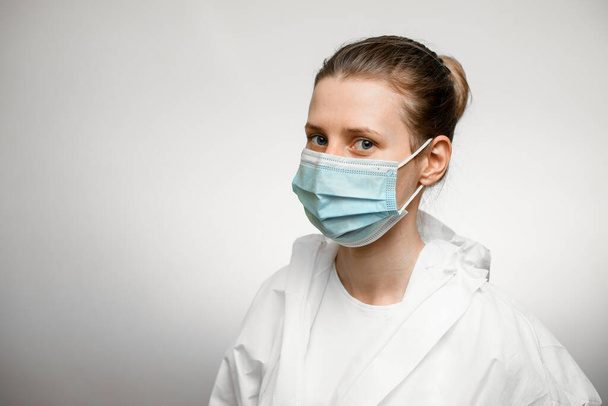 Young female doctor wearing protective suit and medical mask. - 写真・画像