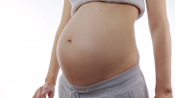 Primer plano de una mujer embarazada acariciando su vientre en cámara lenta y haciendo un corazón con los dedos en el estómago
. - Metraje, vídeo