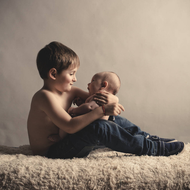 blonďatý chlapec s dítětem v náručí - Fotografie, Obrázek