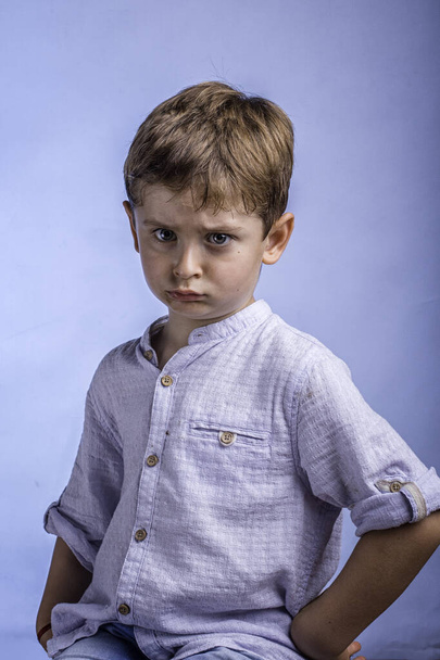 dühös szőke fiú kék háttér - Fotó, kép