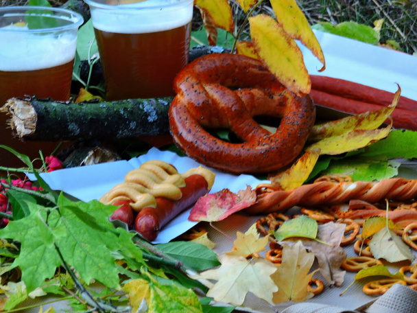 秋のピクニック。10月の祭典を祝うというコンセプト。ビールバイエルンソーセージとプレッツェル。オクトーバーフェスト自然の中で. - 写真・画像