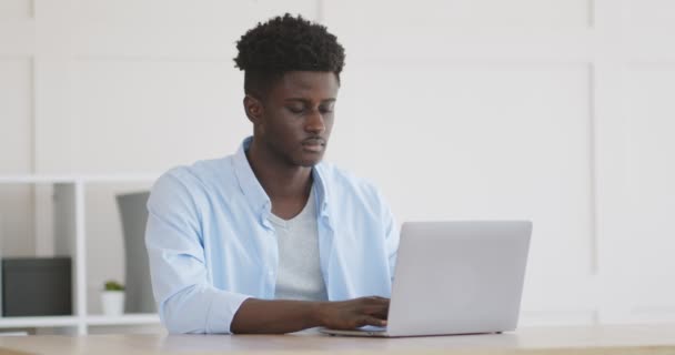 Junger Afrikaner tippt zu Hause im Büro auf Laptop - Filmmaterial, Video