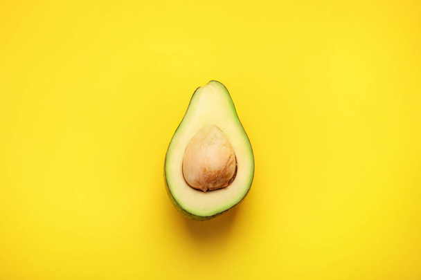 Half of green ripe avocado on yellow background. Top view - Foto, afbeelding