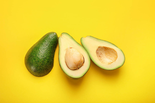 Green ripe avocado on yellow background. Top view - Foto, afbeelding