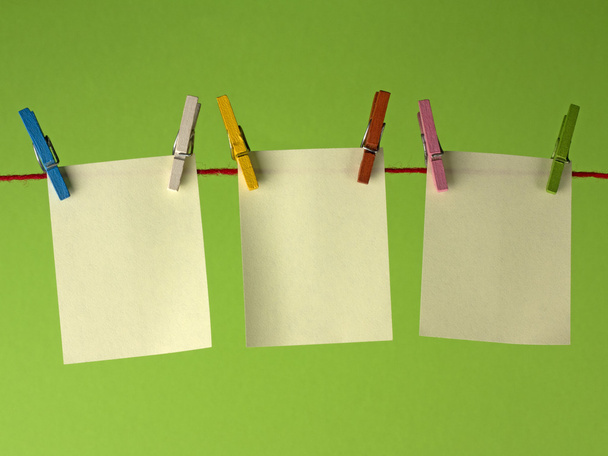 Papeles amarillos pegajosos notas colgando de la clavija de la ropa, sobre un fondo verde
. - Foto, Imagen