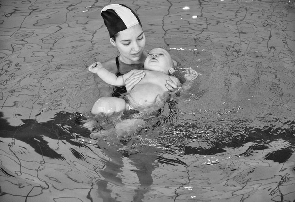 Italy, young mother and her newborn male child in a swiming pool - Photo, Image