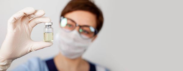 Lekarz lub pielęgniarka w rękawiczkach nitrylowych trzyma w ręku szczepionkę przeciwko grypie, odrze, koronawirusowi COVID-19 - Zdjęcie, obraz