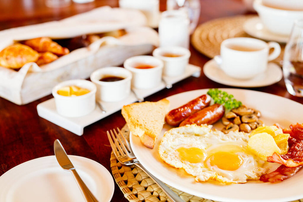 Delicious breakfast with fried eggs, bacon and vegetables - Foto, afbeelding