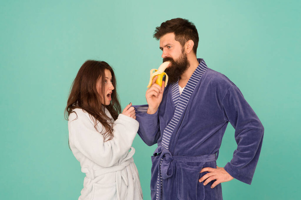 Sweet banana. Seductive hipster eat banana infront of woman. Using seduction tactics in family life. Scene of seduction. Couple in love blue background. Process of seduction. Seduction concept - Photo, Image
