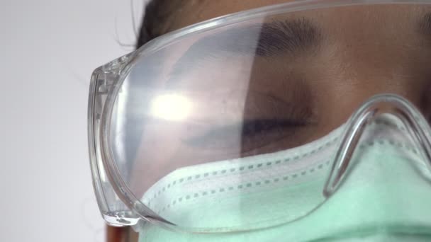 Macro close up of woman surgeon eye, doctor with protective face mask and glasses ready for operation. Essential healthcare professional at hospital. African American female in the disposable mask. - Πλάνα, βίντεο
