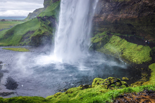 South Region, Iceland - June 9, 2018: Famous Seljalandsfoss waterfall on Seljalands River that has its origin in volcano glacier Eyjafjallajokull - Zdjęcie, obraz