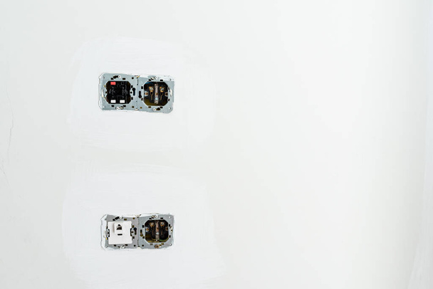 Prises électriques et interrupteurs avec circuits internes visibles sur un mur pendant les travaux de rénovation. - Photo, image