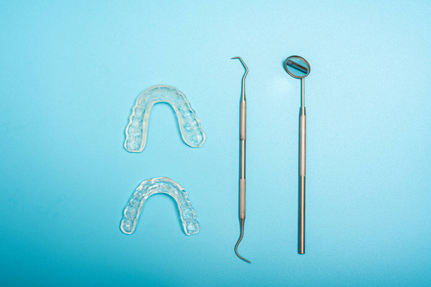 Herramientas dentistas para evitar el bruxismo, dispuestas sobre un fondo azul visto desde arriba
. - Foto, imagen
