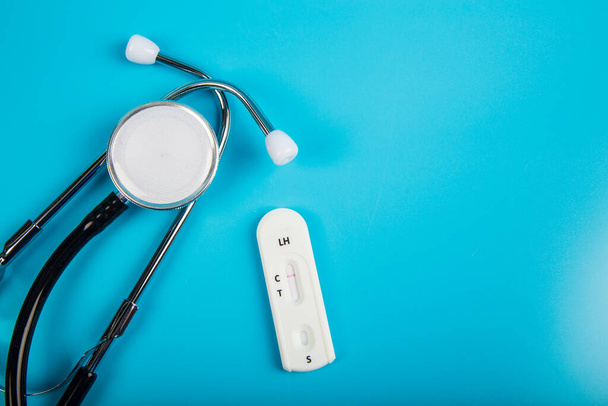 Stethoskop isoliert und schwanger Testkit auf blauem Hintergrund - Foto, Bild