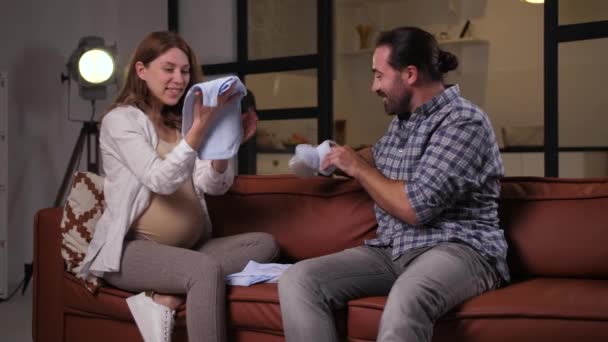 Szczęśliwi przyszli rodzice patrząc na ubrania dla niemowląt - Materiał filmowy, wideo